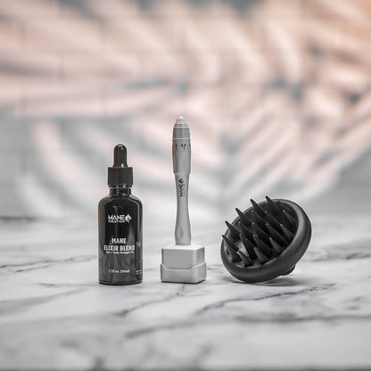 The Mane Solution hair growth bundle featuring the Derma Stamp, Mane Elixir Blend oil, and scalp massager on a marble background